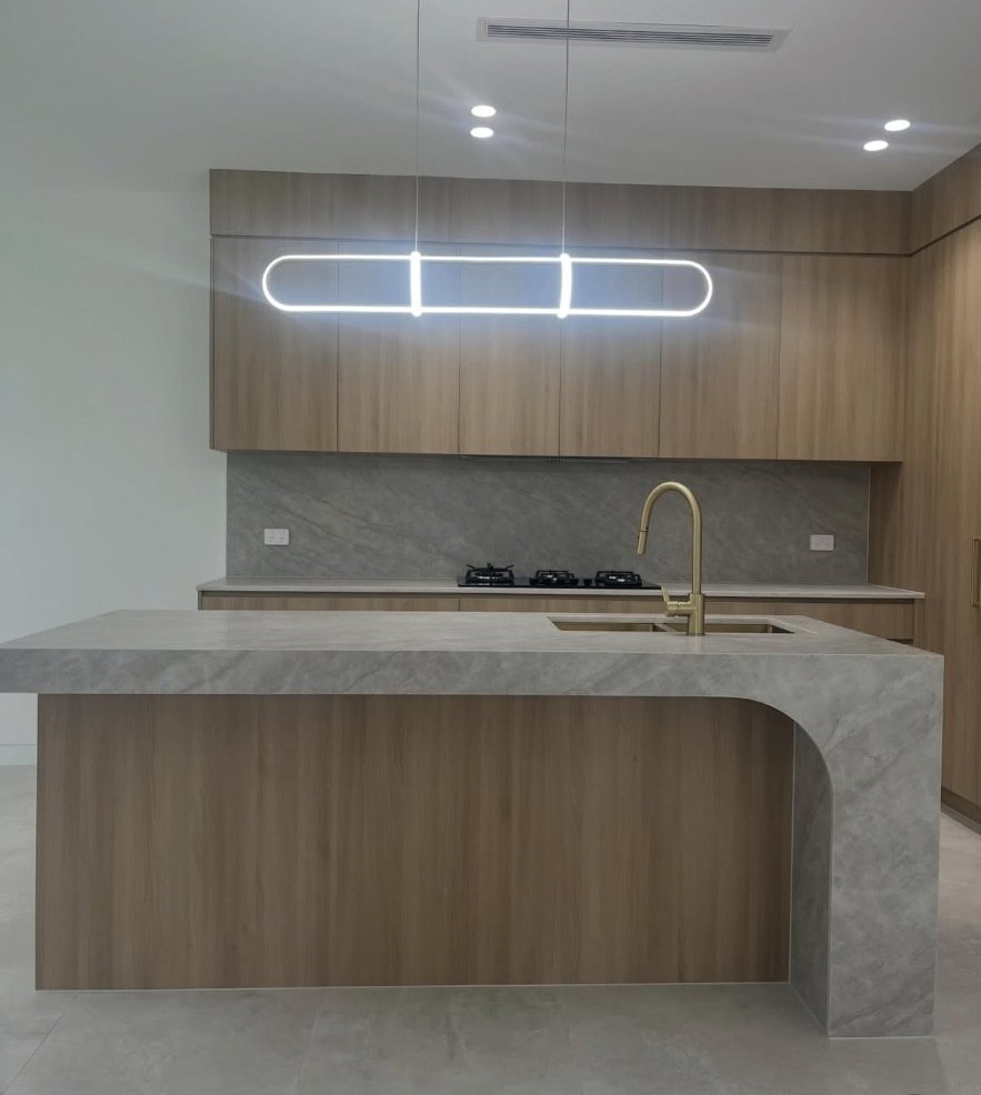 Stone waterfall island and timber kitchen with clean silicone lines sealed for handover